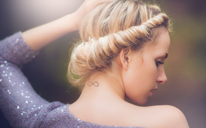 Woman with infinity tattoo and blonde hair in sweater