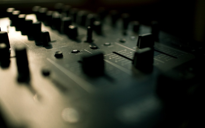Close-up of a DJ mixing console with faders and knobs