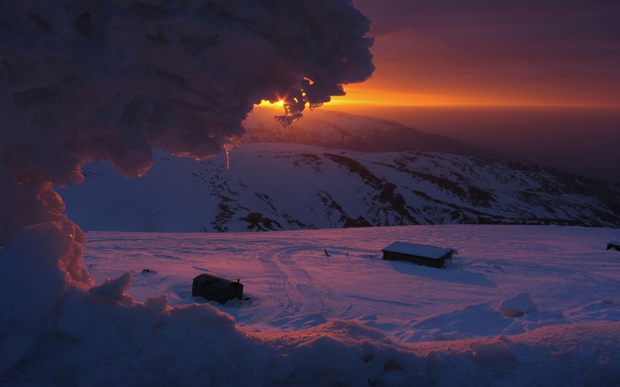 Snowy mountain landscape at sunset with ice formations