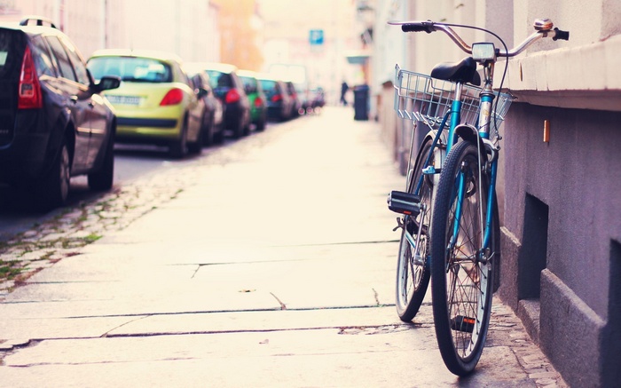 Bicycle parked on a city street next to parked cars