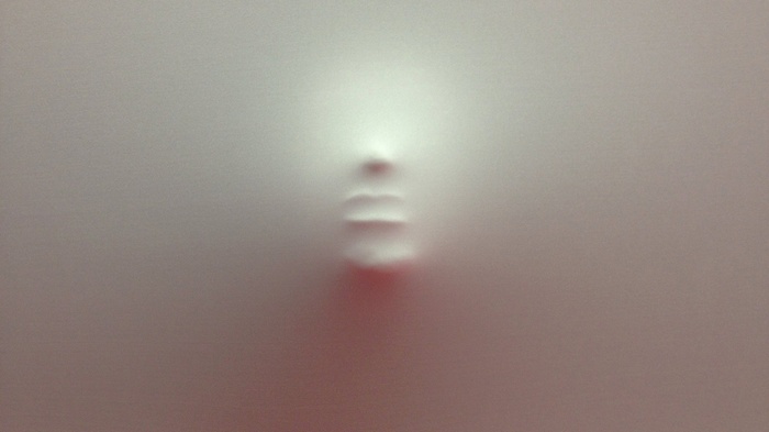 Face pushing through a white wall
