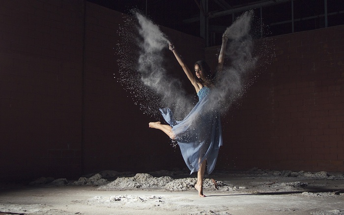 Woman in blue dress dancing with dust