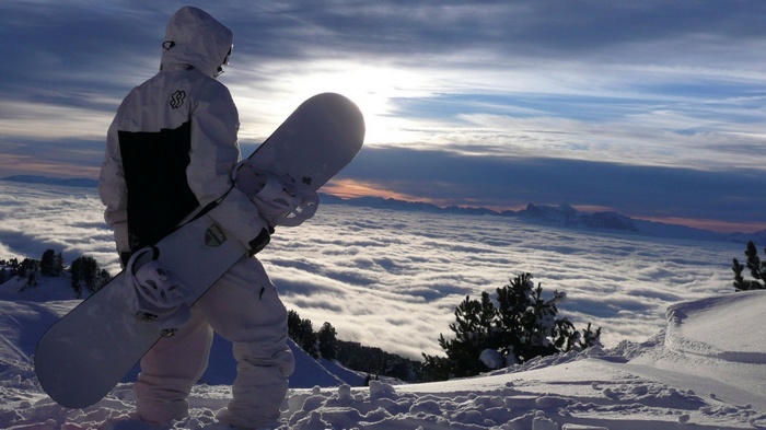 Snowboarder overlooking a sea of clouds at sunset