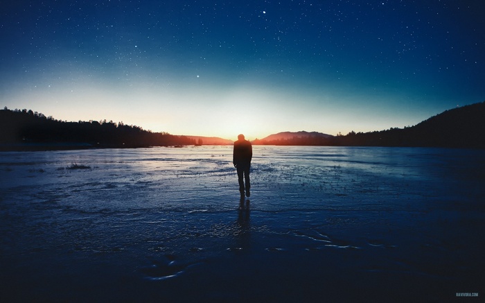 Man walking on ice under starry sky at sunset