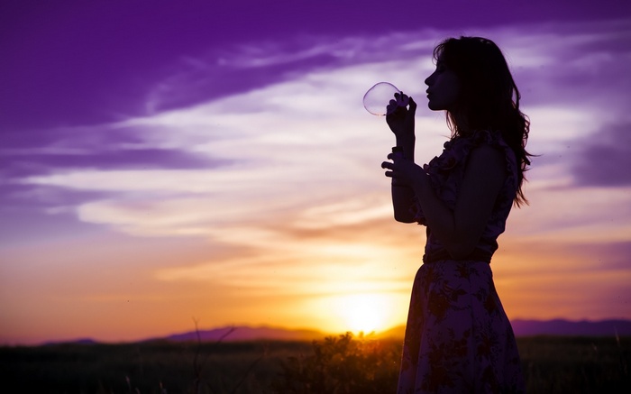 Woman blowing bubbles at sunset