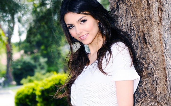Victoria Justice leaning against a tree