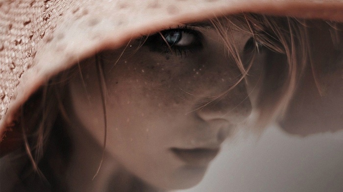 Woman with blue eyes and freckles wearing a hat