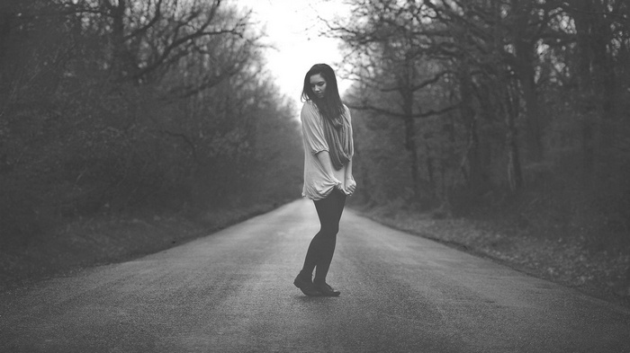 Woman standing alone on a road in a forest