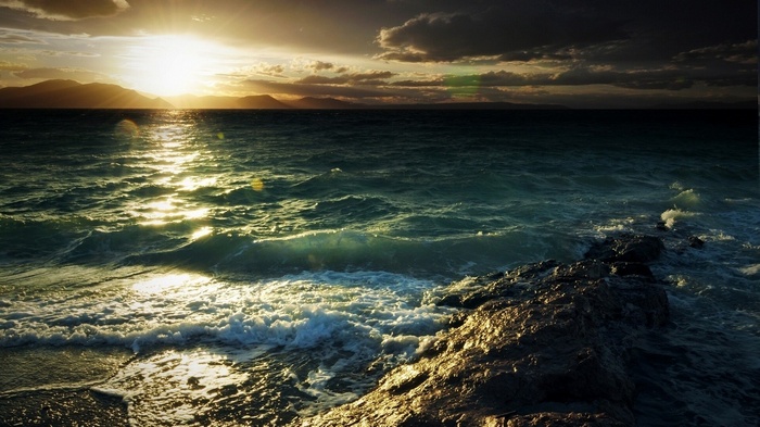 Sunlight reflecting on the sea with mountains in the background