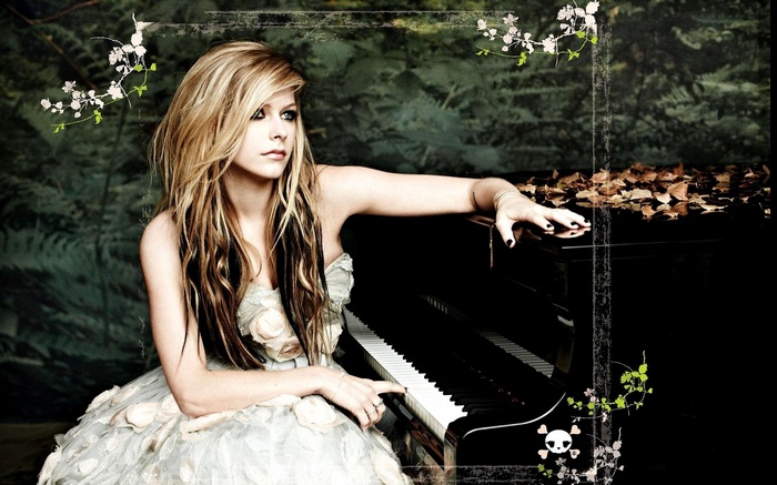 Avril Lavigne sitting by a piano with flowers