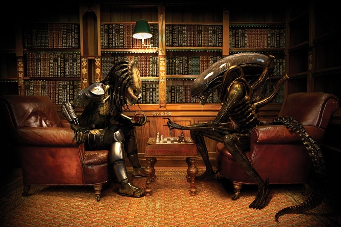 Predator and Xenomorph play chess in a library