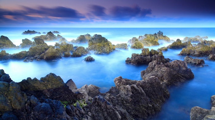 Rocky coastline with misty ocean and purple sky