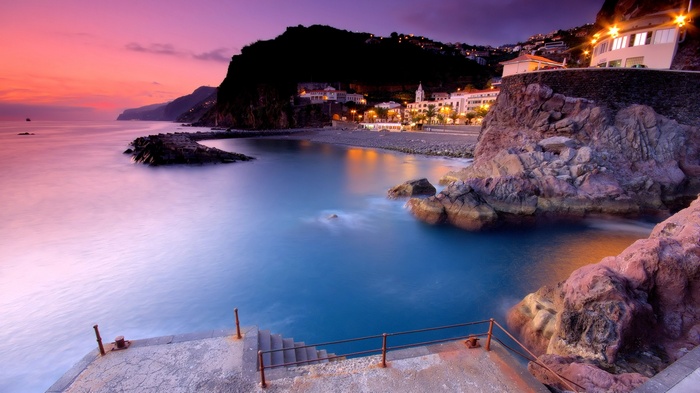 Coastal town at sunset with ocean and cliffs