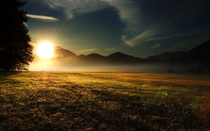 Sunrise over a misty mountain landscape with a field