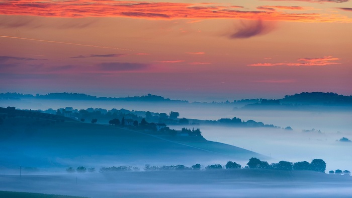 Misty landscape at sunset with rolling hills