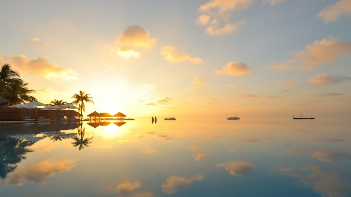 Sunset over a tropical resort with calm sea reflection