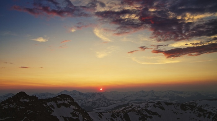 Sunset over snow-capped mountains with colorful clouds