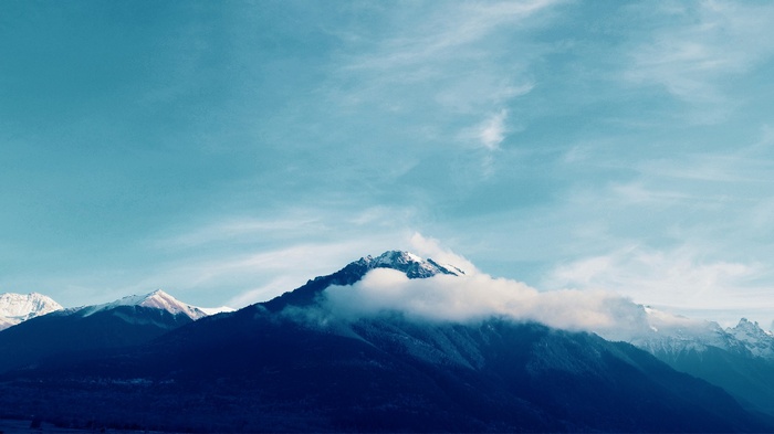 Snow-capped Caucasus mountains under a cloudy sky