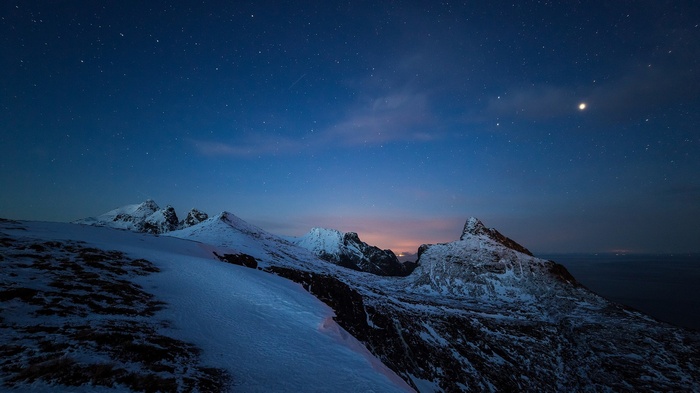 Snowy mountains under a starry night sky