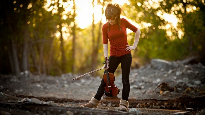 Lindsey Stirling with a violin in a forest