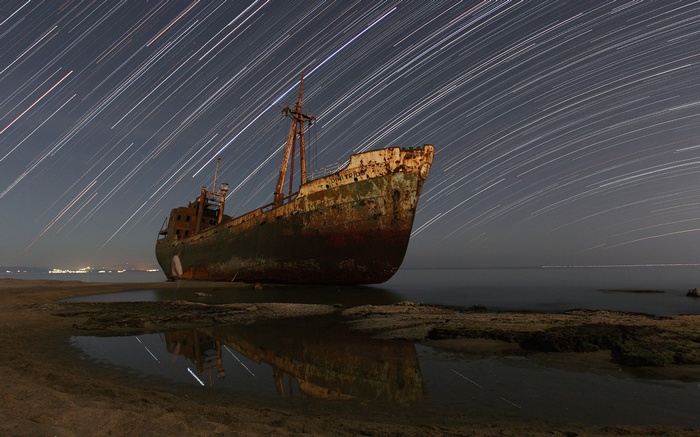 Abandoned shipwreck on a beach with star trails