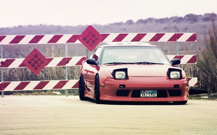 Red Nissan 180SX parked by a construction barrier