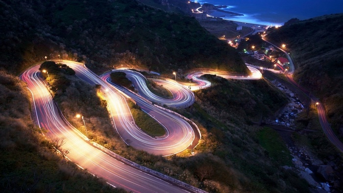 Winding mountain road with light trails at night