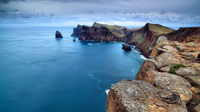 Rocky coast with blue sea under cloudy sky