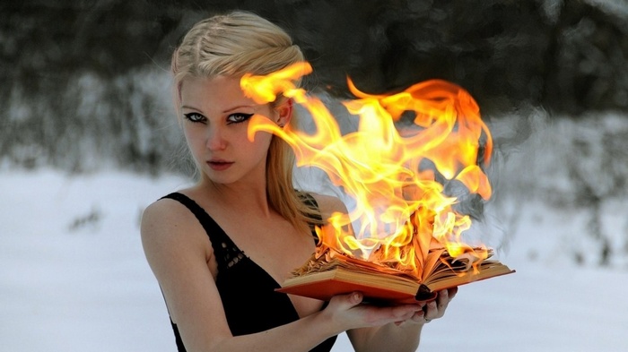 Woman holding a burning book in the snow