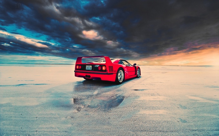 Red Ferrari F40 on a wet plain under dramatic clouds