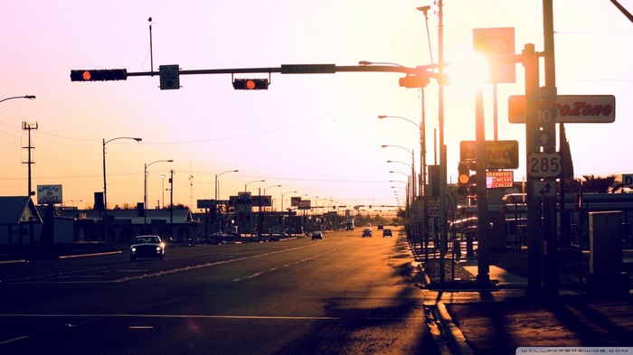 Street scene with traffic lights and sun rays at sunset