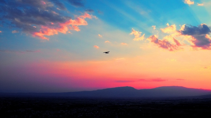 Airplane flying over mountains at sunset