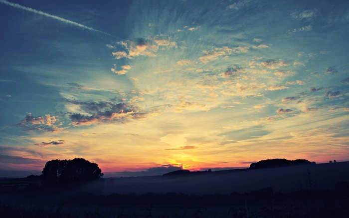 Sunset over a misty landscape with clouds