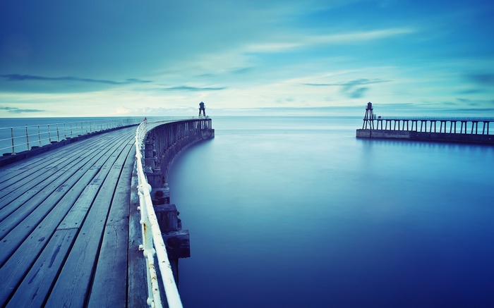 Wooden pier with lighthouses on the sea horizon