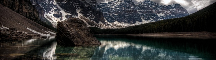 Moraine Lake with a large rock in the foreground and mountains