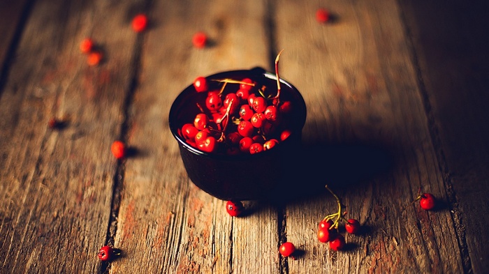 Red berries in a black bowl on a wooden table