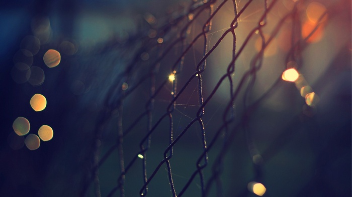 Macro shot of a chain-link fence with bokeh lights
