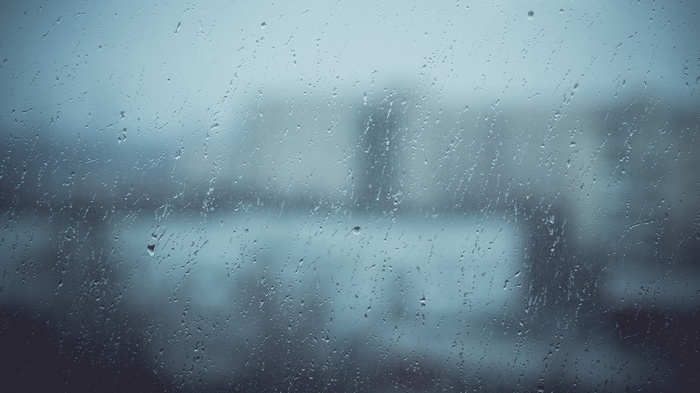Raindrops on a window pane with blurred buildings