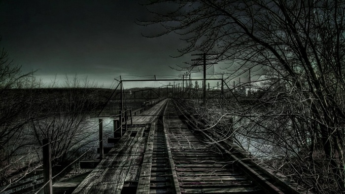 Abandoned railway bridge over water at dusk