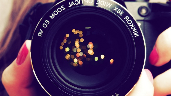 Nikon camera lens with bokeh reflection and painted nails