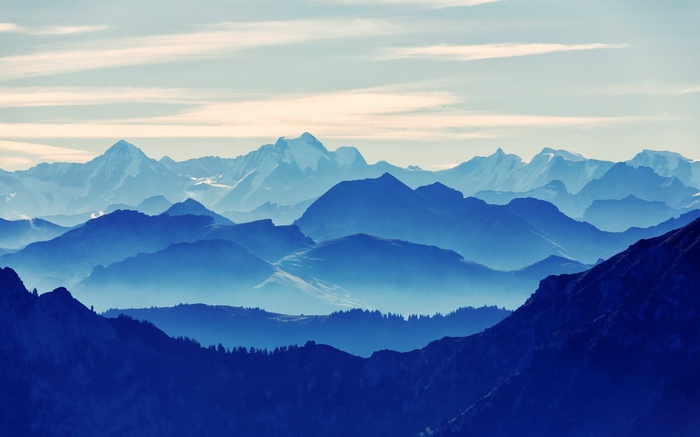 Layered blue mountains under a pale sky