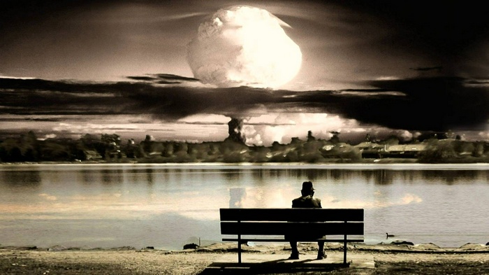 Man watches atomic bomb explosion from a bench