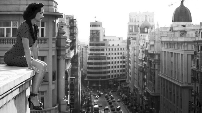Vintage woman sitting on a building overlooking a city street