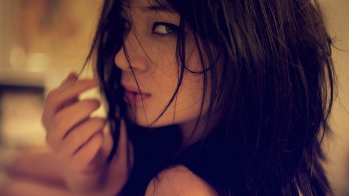 Brunette woman with dark hair looking over her shoulder