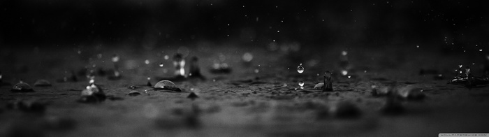 Monochrome water drops falling on a dark surface