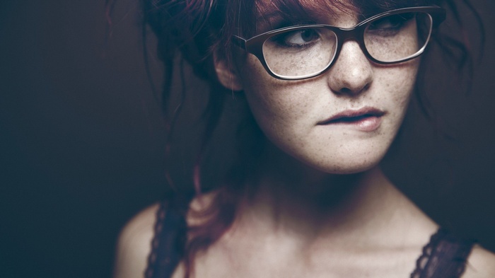 Woman with freckles and glasses biting her lip