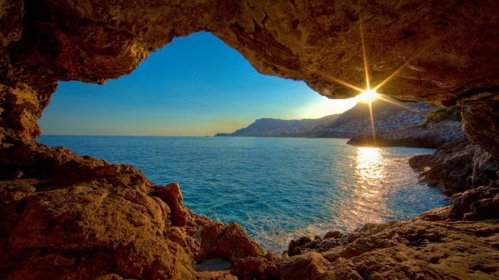 View of the sea from a cave entrance at sunset