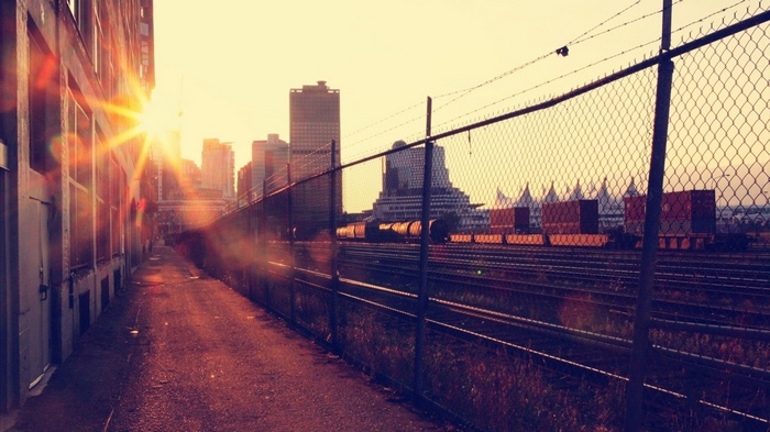 Sun rays over a rail yard with a city skyline