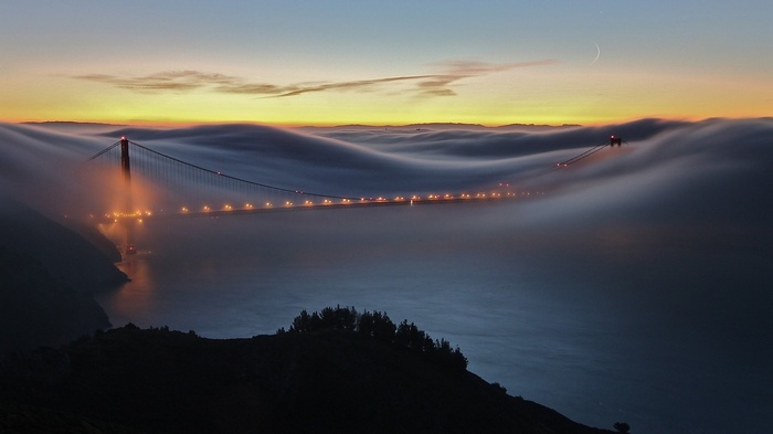 Golden Gate Bridge shrouded in fog at sunrise