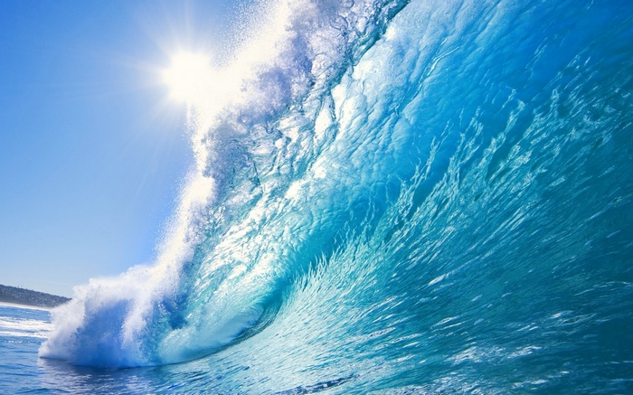 Sun shining on a large blue ocean wave